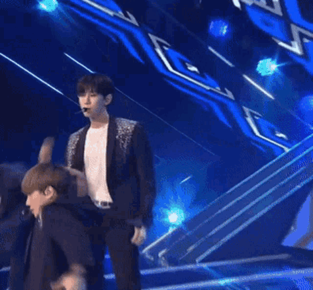 a man in a black jacket and white shirt is dancing on a stage