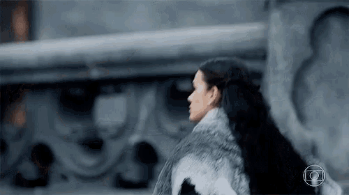 a woman wearing a fur coat is walking in front of a building .