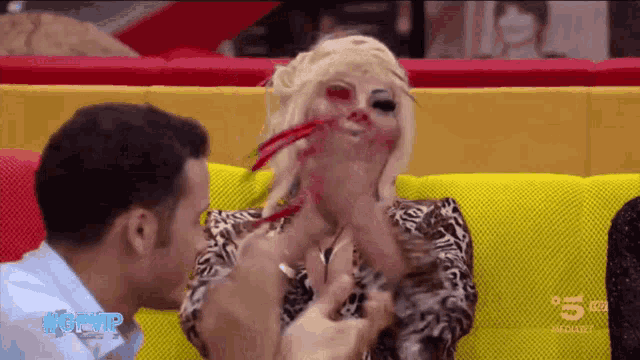 a woman with blood on her face is being kissed by a man in front of a screen that says #gvip