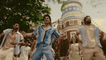 a group of people are dancing in front of a building that says grand hotel on it