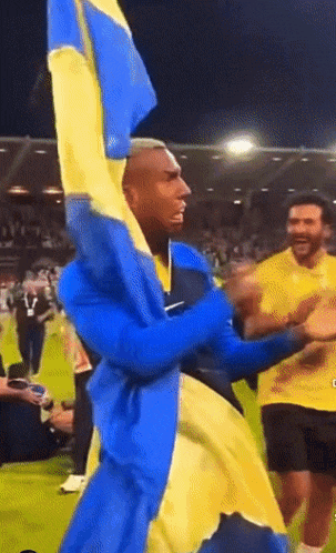 a man in a blue and yellow outfit holds a yellow and blue flag