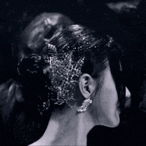 a woman wearing a bun and earrings stands in the rain