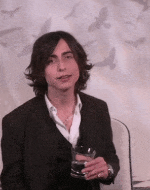 a man in a suit holds a glass of water