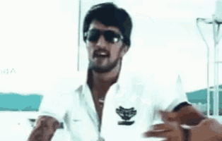a man with a beard is wearing sunglasses and a white shirt and is dancing on a boat .
