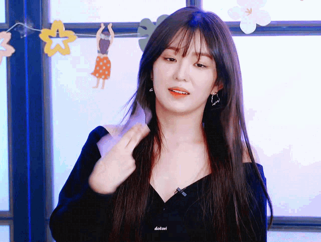 a woman with long hair is standing in front of a window wearing a black off the shoulder top and earrings