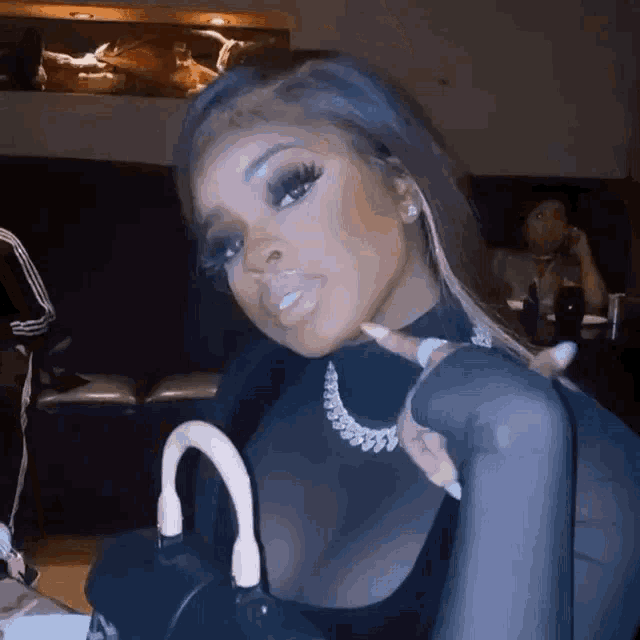 a woman is sitting at a table with a purse and a necklace .