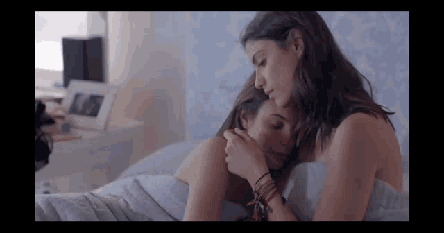 two women are hugging each other in a bed