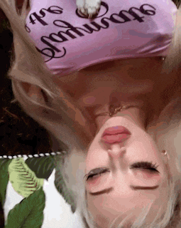 a woman in a pink crop top is laying upside down with her head down .