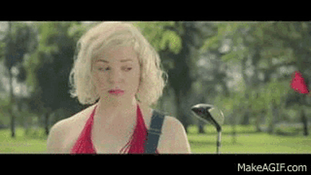 a woman is standing on a golf course with a golf club .