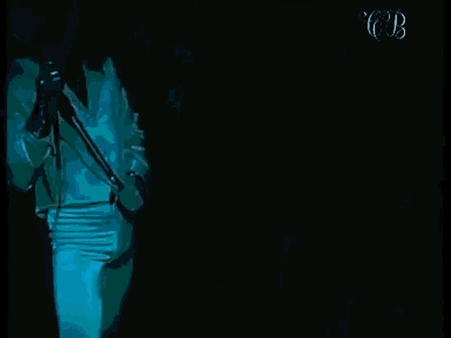 a man in a white shirt is singing into a microphone on a stage .