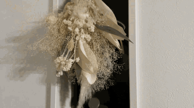 a bouquet of dried flowers hangs on a door