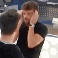 a man is covering his ears while another man looks on .