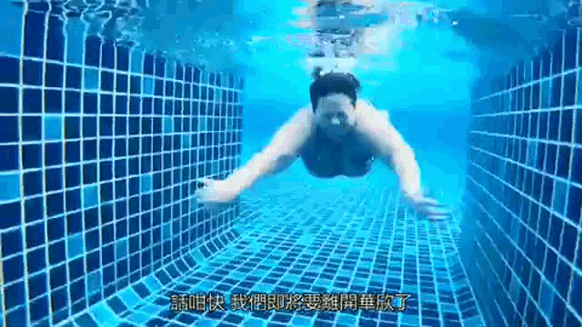 a person is swimming underwater in a pool with chinese writing