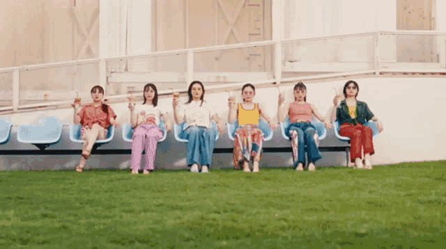 a group of women are sitting in a row holding drinks in their hands
