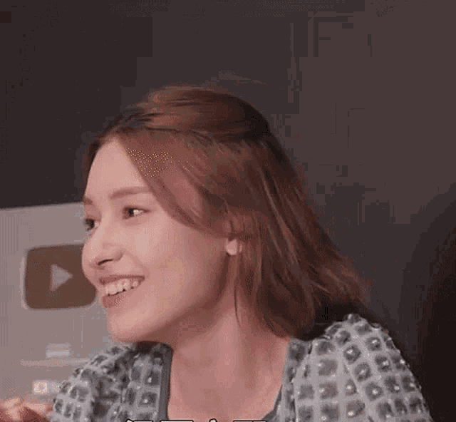 a woman is smiling while sitting at a table with a laptop in front of her .