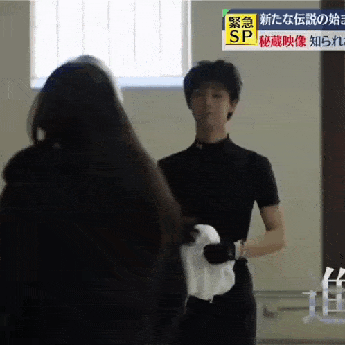 a man in a black shirt is standing next to a woman and holding a towel .