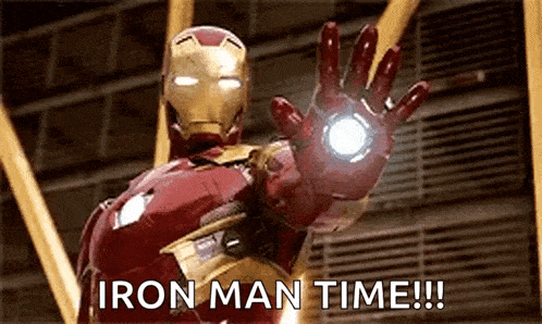 iron man is standing in front of a building and waving his hand in the air .
