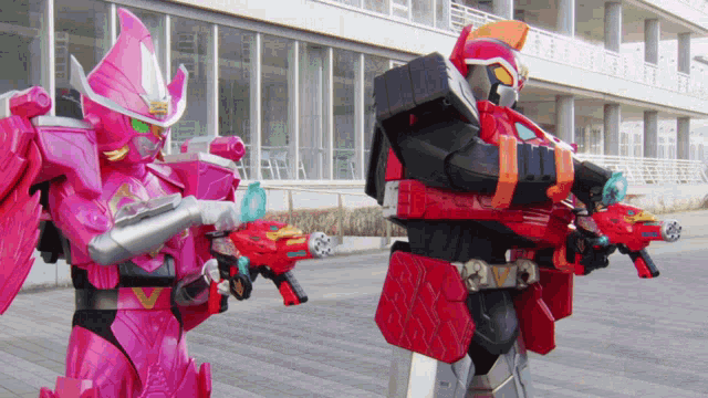 a pink robot and a red robot are standing next to each other with guns