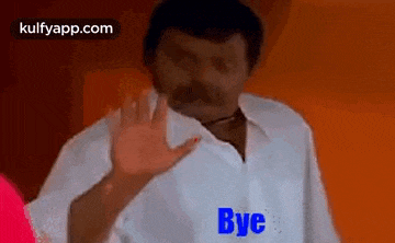 a man in a white shirt is waving his hand with the words `` bye '' written on it .