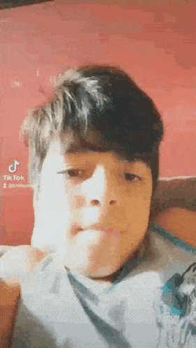 a young boy is making a funny face and looking at the camera while laying on a bed .