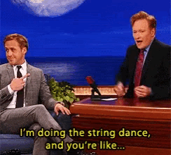 two men are sitting at a table and one of them is saying " i 'm doing the string dance "