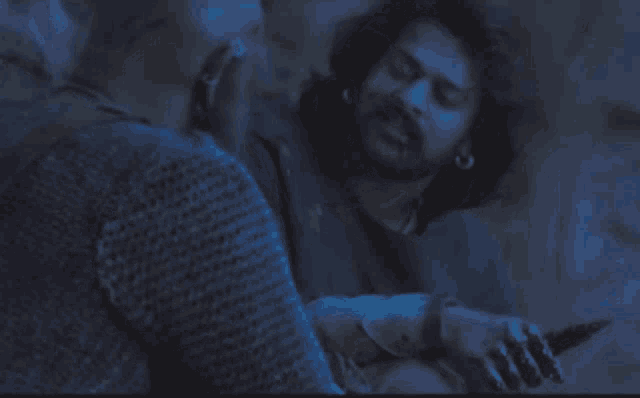 a man with a beard is talking to another man in a blue light