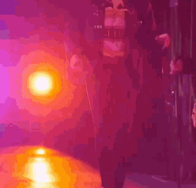 a person is standing in front of a microphone in a purple and orange light