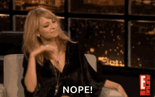 a woman in a black dress is sitting in a chair and making a funny face and saying nope .