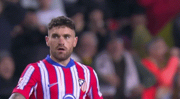 a soccer player in a red and white striped jersey is standing on a field .