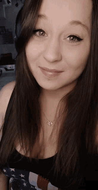a woman wearing headphones and a necklace with the letter t on it