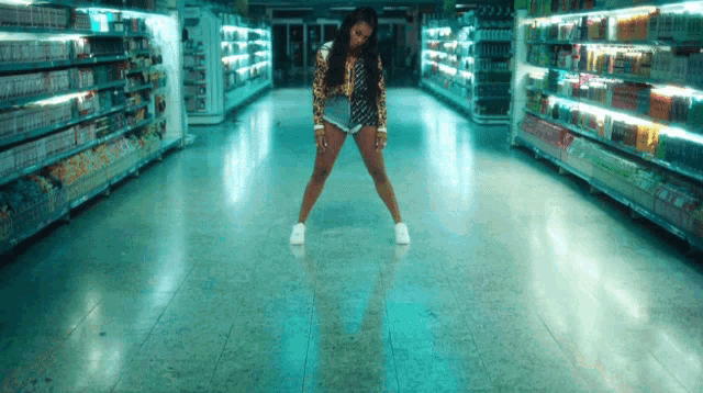 a woman in a leopard print top and shorts is dancing in a grocery store aisle