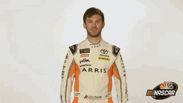a man in a toyota racing suit is holding a yellow ribbon .