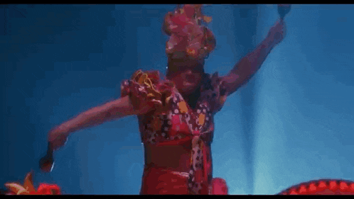 a woman in a red dress is dancing in the water with a snake .