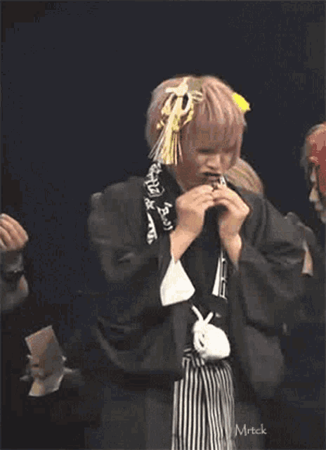 a man with pink hair is wearing a kimono and a scarf .