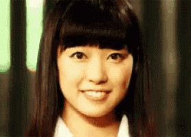 a close up of a woman 's face with long black hair and bangs .