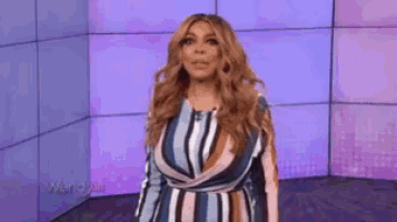 wendy williams is wearing a striped dress and standing in front of a purple wall .