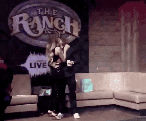 a couple dancing in front of a sign that says the ranch