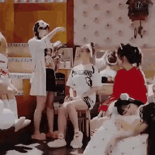 a group of women are gathered in a room with a clock on the wall behind them
