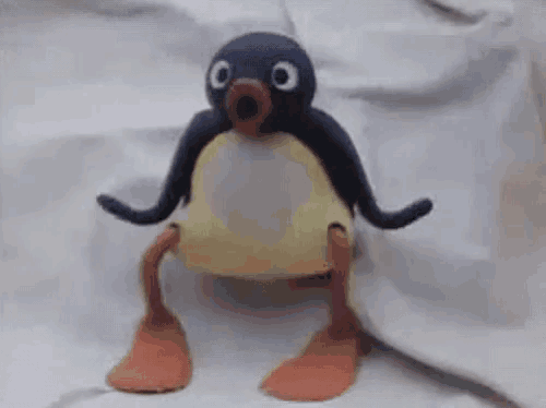 a stuffed penguin is standing on its hind legs on a white cloth .