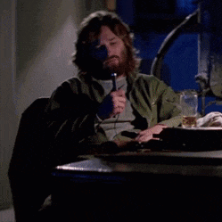 a man with a beard is sitting at a table with a microphone in his hand