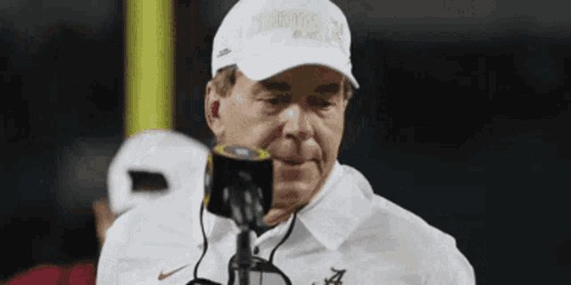 a man wearing a white hat that says alabama is talking into a microphone