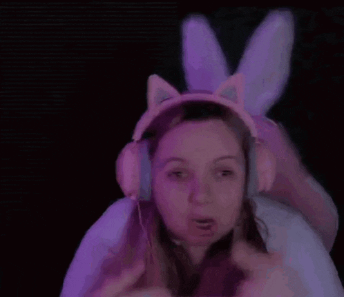 a girl wearing bunny ears and headphones is making a funny face .
