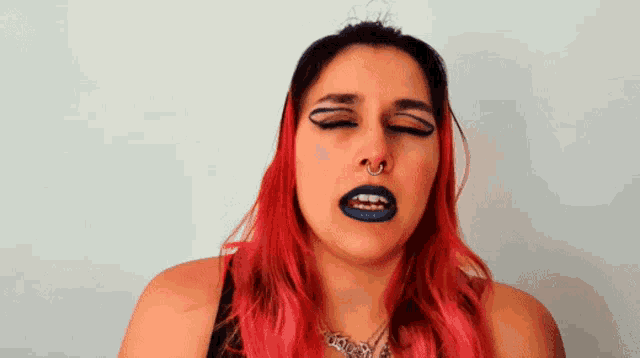a woman with red hair and blue lips is making a funny face