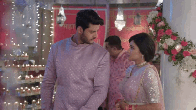 a man and a woman are standing next to each other in a room with flowers and lights