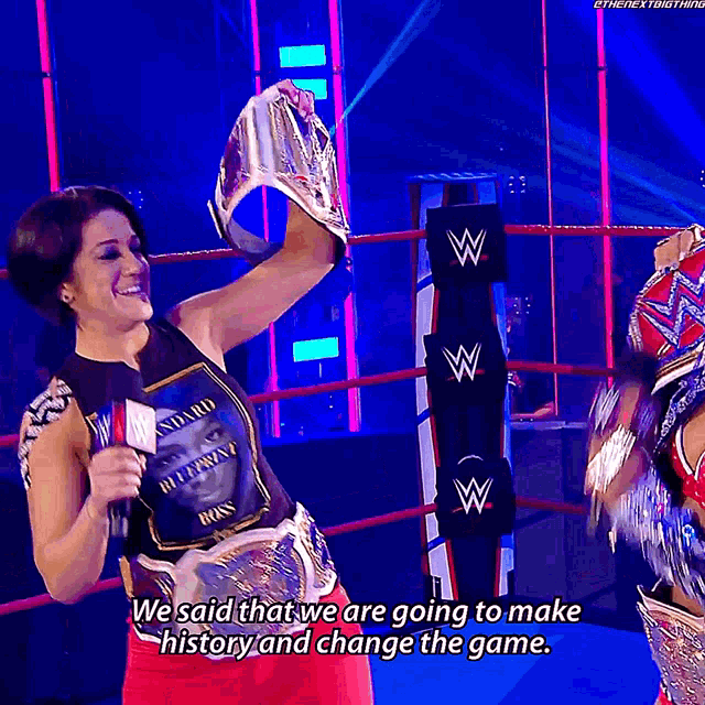 a woman in a wrestling ring holds up a trophy and says we said that we are going to make history