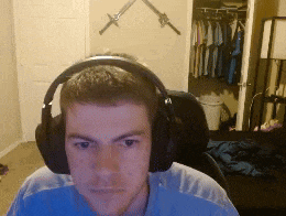 a man wearing headphones looks at the camera in a room with swords on the wall