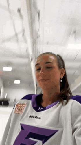a girl wearing a white and purple hockey jersey with the letter f on it