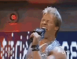 a wrestler is singing into a microphone in front of a sign that says wwe