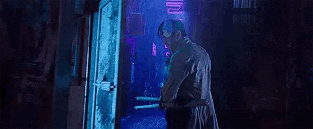 a man is standing in front of a door in a dark room holding a knife .