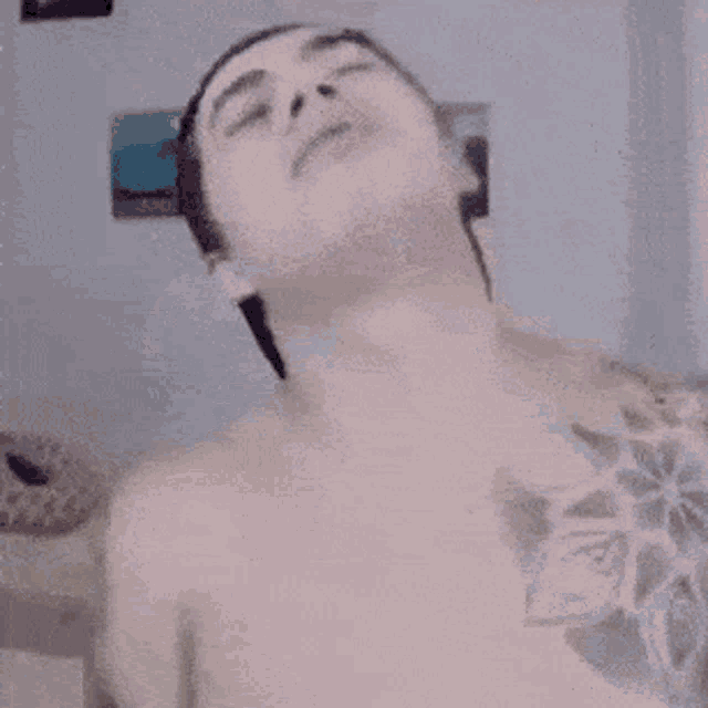 a shirtless man with a tattoo on his chest looks up at the camera .